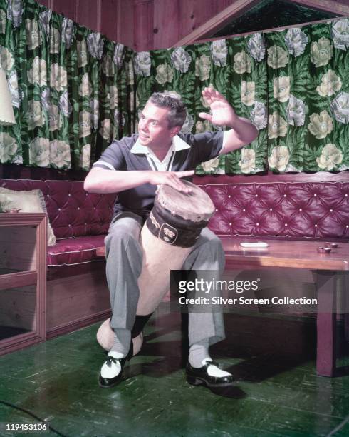 Desi Arnaz , Cuban-born US musician and actor, beating a conga drum with his hand in a publicity still issued for the US television series, 'I Love...