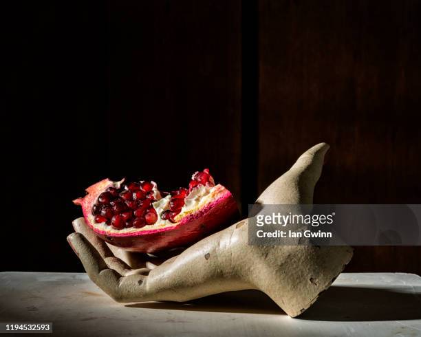 pomegranate in mannequin hand - ian gwinn stock pictures, royalty-free photos & images