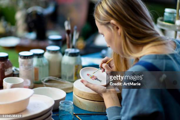 young woman painting nutcracker on christmas ceramics in her pottery workshop, small business concept - craft stock pictures, royalty-free photos & images
