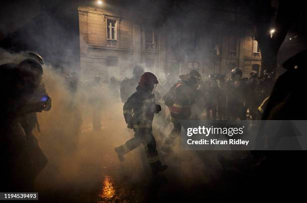 French fireman run through clouds of tear gas at Place de la Nation as thousands take to the streets of Paris in support of the National Strike on a...