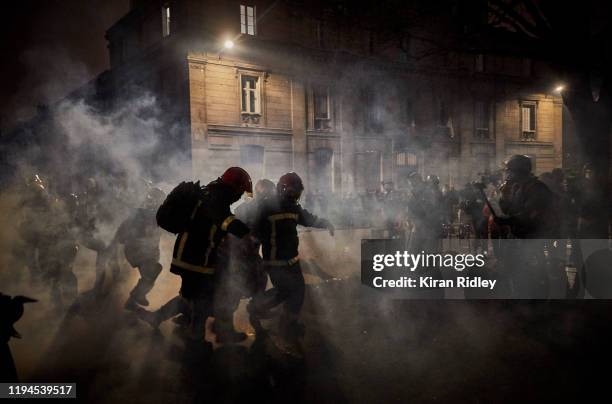 French fireman help an injured protestor to safety through clouds of tear gas at Place de la Nation as thousands take to the streets of Paris in...