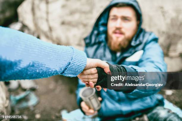 obdachloser mann auf der straße bekommt hilfe von frau - betteln soziales thema stock-fotos und bilder