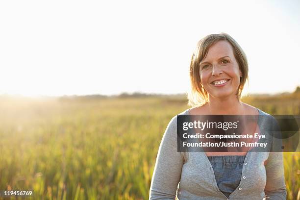 woman smiling in field - compassionate eye foundation stock-fotos und bilder