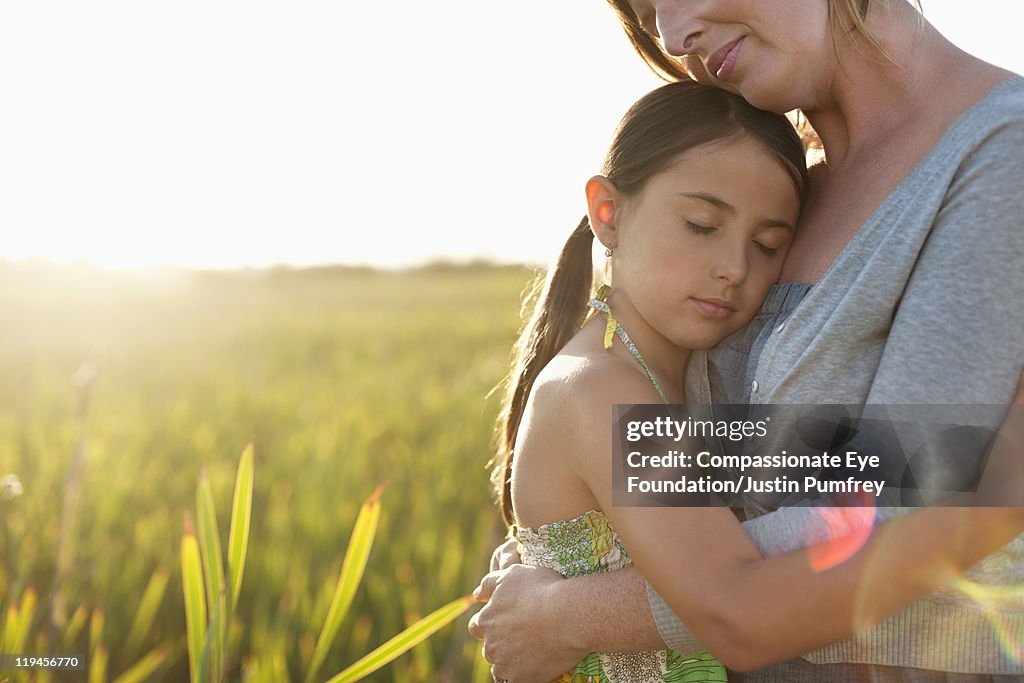 Mother and daughter embracing in a field