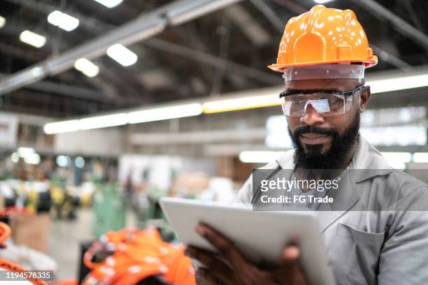 mann arbeitet mit seinem digitalen tablet in der fabrik - glory tube stock-fotos und bilder