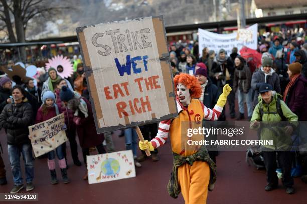 Man dressed as Ronald McDonald, the clown character used as the primary mascot of the McDonald's fast-food restaurant chain, holds a placard as he...