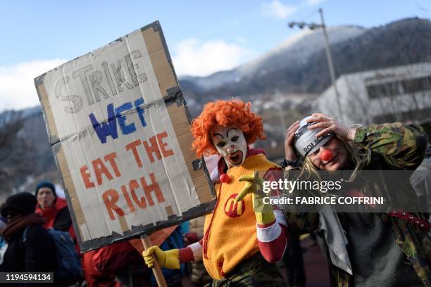 Man dressed as Ronald McDonald, the clown character used as the primary mascot of the McDonald's fast-food restaurant chain, holds a placard as he...