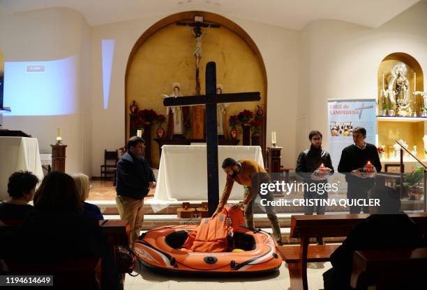 Parishioners place an inflatable boat and life jackets at the bottom of the cross of Lampedusa in the Saints Justa and Rufina church during the...