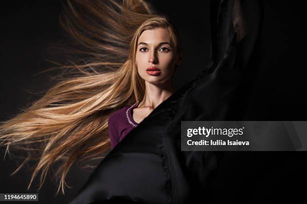 female model with long fluttering hair against black wall - maroon hair stock pictures, royalty-free photos & images