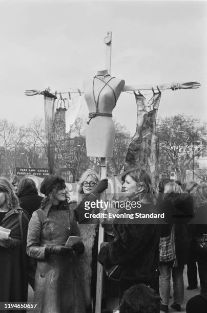 Three women hold a dummy attached to a prop in the shape of a crucifix as they take part in a Women's Liberation Movement march from Hyde Park to...