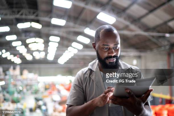 manager focalizzato che utilizza tablet digitale in una fabbrica - usare un tablet foto e immagini stock