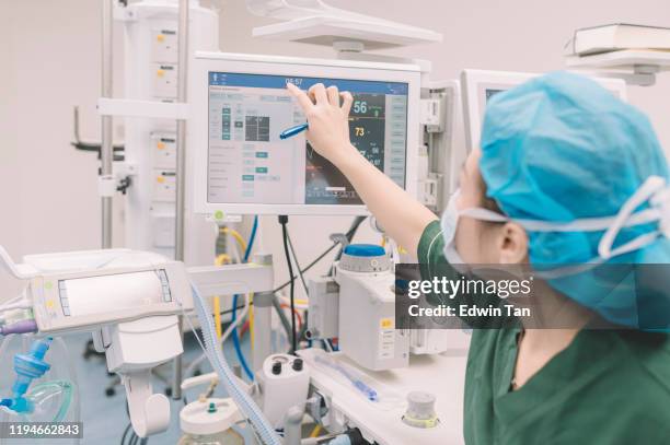 een aziatische chinese anesthesist die werkt in het bedienings theater controle op de monitor - bewakingsapparatuur stockfoto's en -beelden