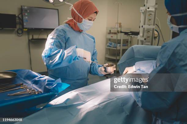 2 asian female surgeon and nurse conducting a surgery on an asian chinese senior woman on her abdomen in the operating room of hospital