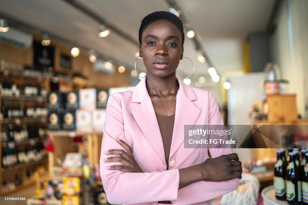 Retrato de una empresaria seria / dueña de negocios de pie con los brazos cruzados en un mercado