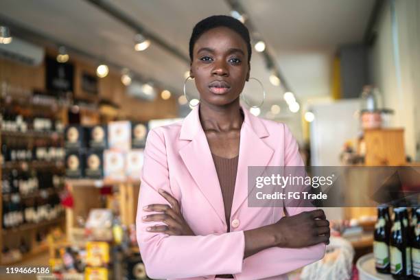 portrait of a serious businesswoman/ business owner standing with arms crossed in a market - strict lady stock pictures, royalty-free photos & images