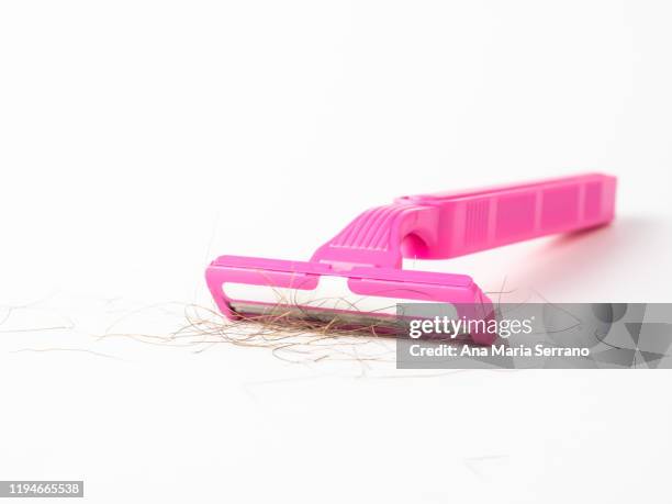 close up of disposable pink razor with hairs between the blades on a white background - vello pubico fotografías e imágenes de stock