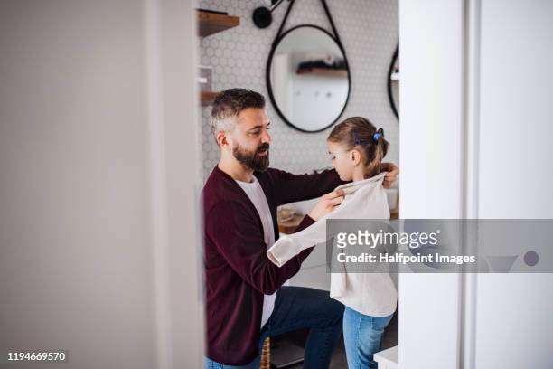 mature father and his small daughter in bathroom indoors at home, getting dressed. - child getting dressed stock-fotos und bilder
