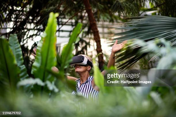 a portrait of mature woman with vr glasses standing outdoors, green business concept. - social impact stock pictures, royalty-free photos & images
