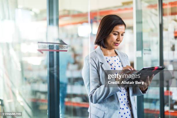 female businesswoman using tablet computer in a small business - factory owner stockfoto's en -beelden