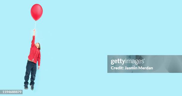 conceptual image of flying little boy on blue background - child balloon studio photos et images de collection