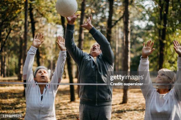 multigenerational group of people plays volleyball - senior kicking stock pictures, royalty-free photos & images