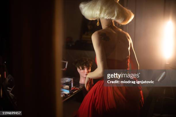 de koningin van de sleep in elegante rode kleding die zich in kleedkamer bevindt - diva human role stockfoto's en -beelden