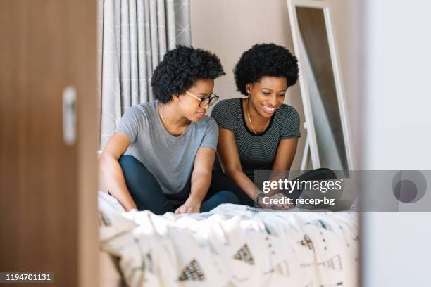 zwarte tweeling zusters genieten van hun tijd thuis - identical twins stockfoto's en -beelden