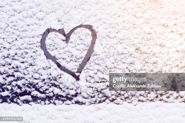 the heart is painted on the glass of the car, on the background of snow. symbol of love, romance, valentine's day. - snow melting on car stock pictures, royalty-free photos & images