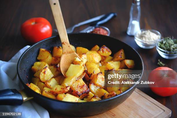 baked in the oven potatoes with spices in a pan on a wooden table. the concept of delicious and healthy home-cooked food. rustic style. organic vegetables, vegan and vegetarian recipe. - fried potato stock pictures, royalty-free photos & images