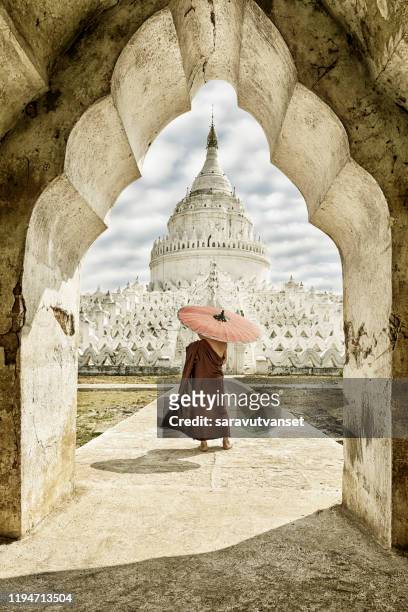 backside of burmese buddhist novice monk who holding umbrella stand in front of mya tien dan pagoda (taj mahal of myanmar) - bagan stock pictures, royalty-free photos & images