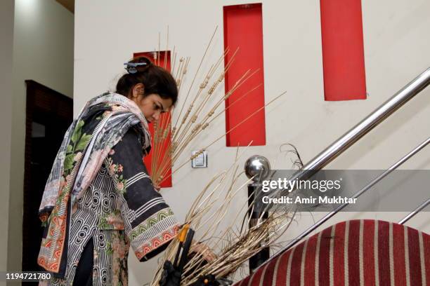 a woman decorating her home with dry plants - pakistan women stock pictures, royalty-free photos & images