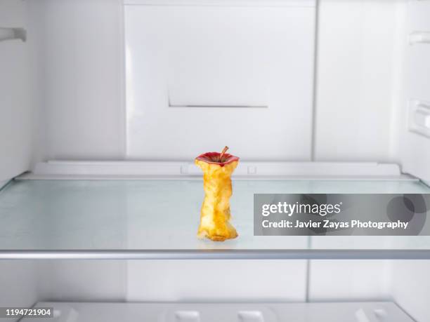 apple core in an empty refrigerator - kühlschrank leer stock-fotos und bilder