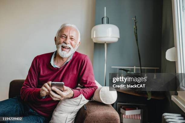 portrait of senior men at home using smart phone - senior comfortable stock pictures, royalty-free photos & images