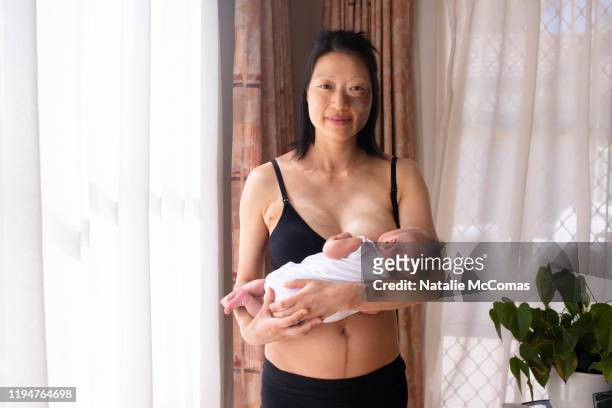 one young woman holding newborn baby at home