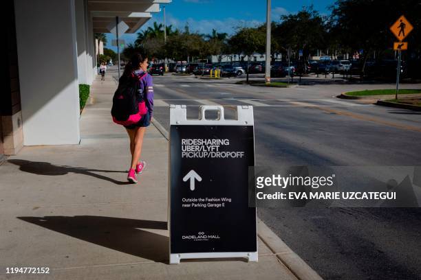 Woman passes by an Uber/Lift sign at Dadeland Mall in Miami on January 9, 2020. - Every year, the American football season ends with the vast...