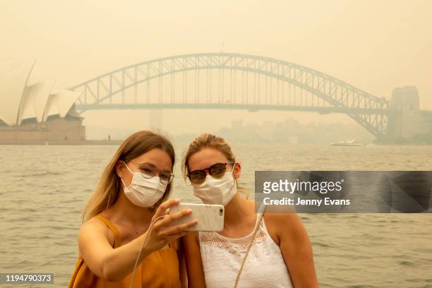 German tourists Julia Wasmiller and Jessica Pryor take a selfie at Mrs Macquarie's chair, wearing face masks due to heavy smoke on December 19, 2019...