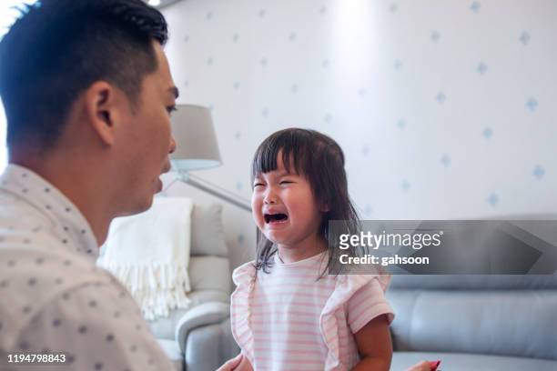 close up of asian father consoling crying daughter - tantrum stock pictures, royalty-free photos & images