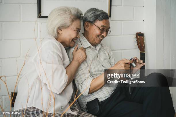 Asian senior couple at home looking at photo from digital camera