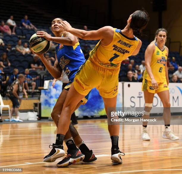 Alice Kunek of the Flames falls to ground as Marte Grays of the Spirit prepares to have a shot at goal during the round 10 WNBL match between the...