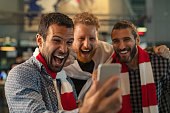 Excited supporters watching football match on phone
