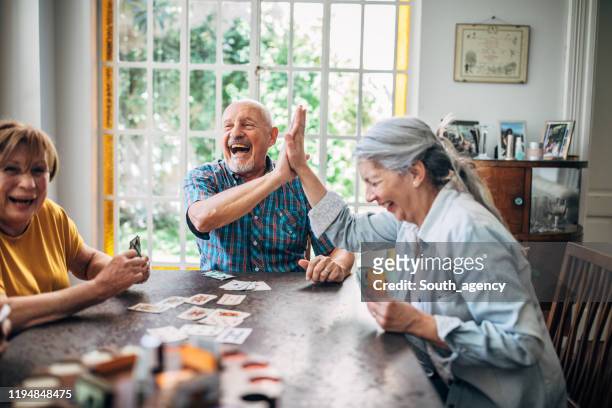 senior people playing cards in nursing home - senior adult stock pictures, royalty-free photos & images