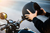 Motorcycle couple holding helmets in hands .