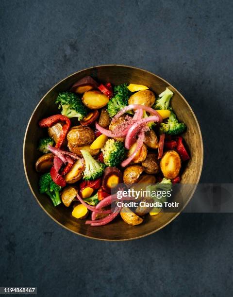 bowl of potato salad with broccoli and onion on black background - saladekom stockfoto's en -beelden