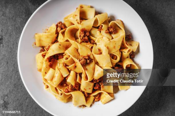 a bowl of papardelle pasta on black background - フェットチーネ ストックフォトと画像