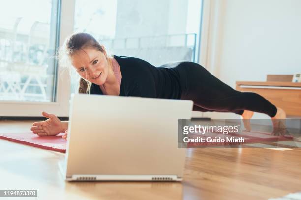 woman doing sport in front of laptop. - woman sports training stock pictures, royalty-free photos & images