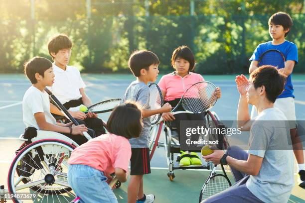 a tennis coach having a meeting with young students, some in a wheelchair and some standing - japanese tennis stock-fotos und bilder