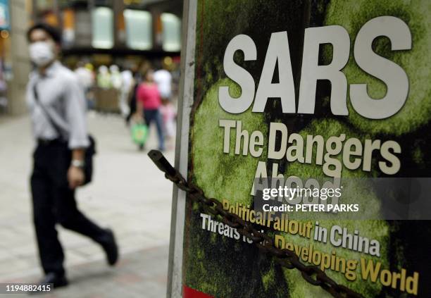 Man walks past a news headline on a newstand wearing mask to protect against SARS on a street in Hong Kong 06 May 2003. Six more people have died 06...