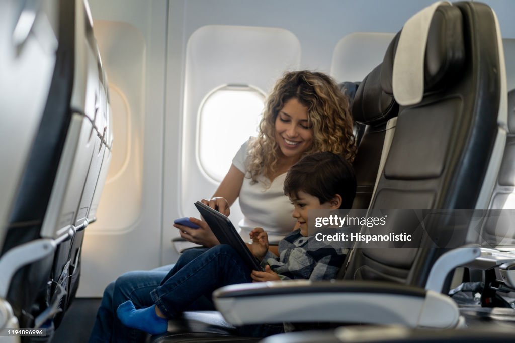 Loving mother and son playing with tablet during a flight looking very happy