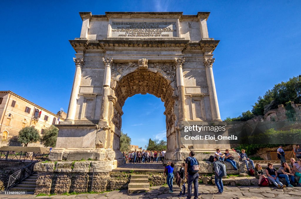Tourists are walking around Arco di Tito, Rome, Italy