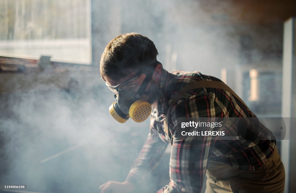 Carpenter with mask and glasses in smoke